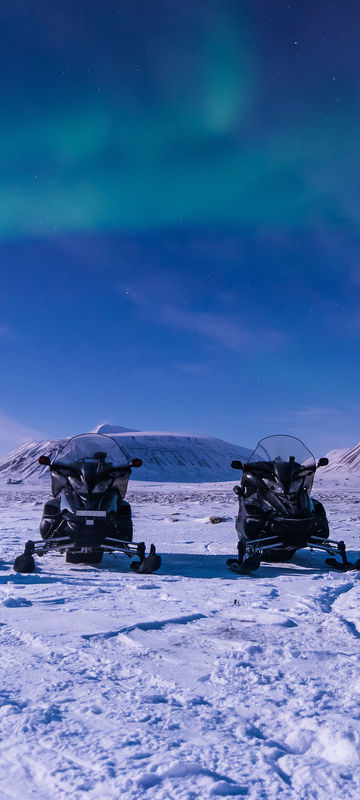 svalbard longyearbyen snowmobiles with aurora istk